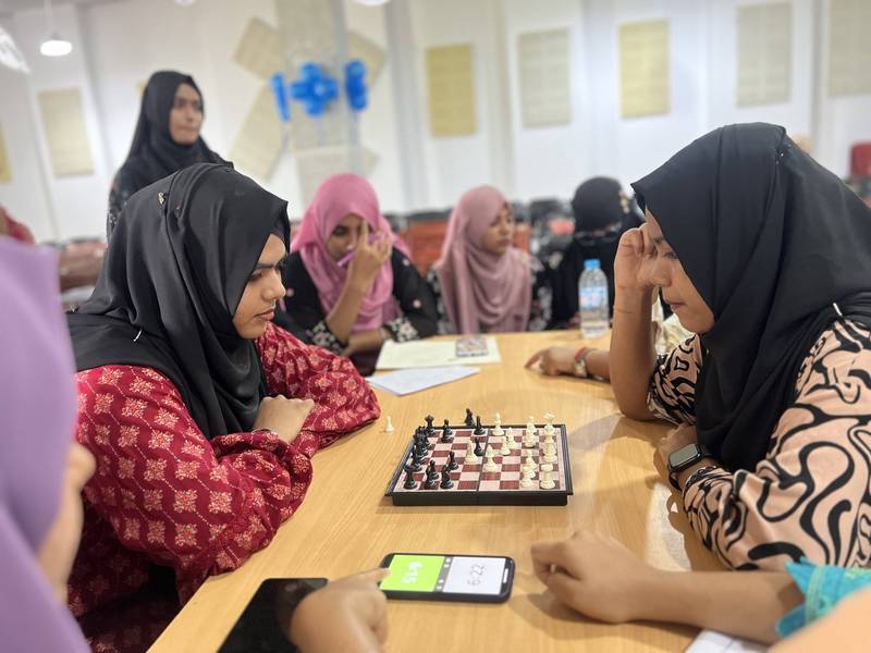 Two students playing chess with a game timer